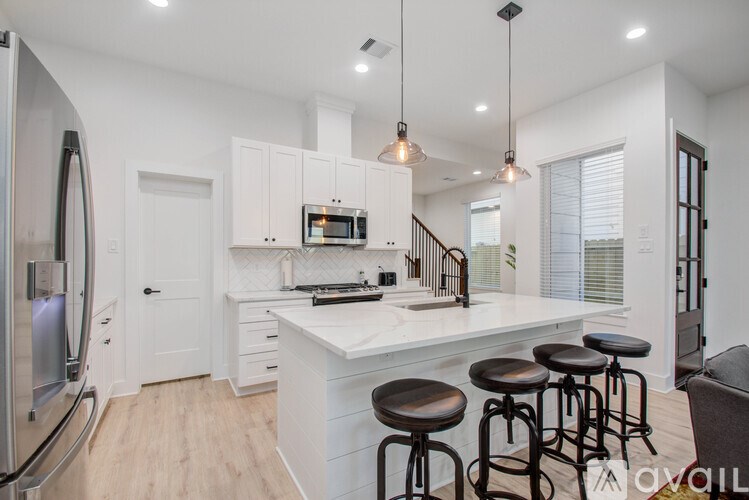 A kitchen with white cabinets and a white island with bar stools.