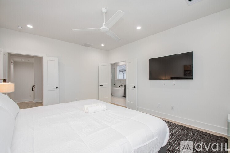 A bedroom with a large bed and a flat screen TV mounted on the wall.