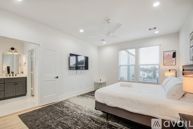 A bedroom with a bed, a television, and a rug.