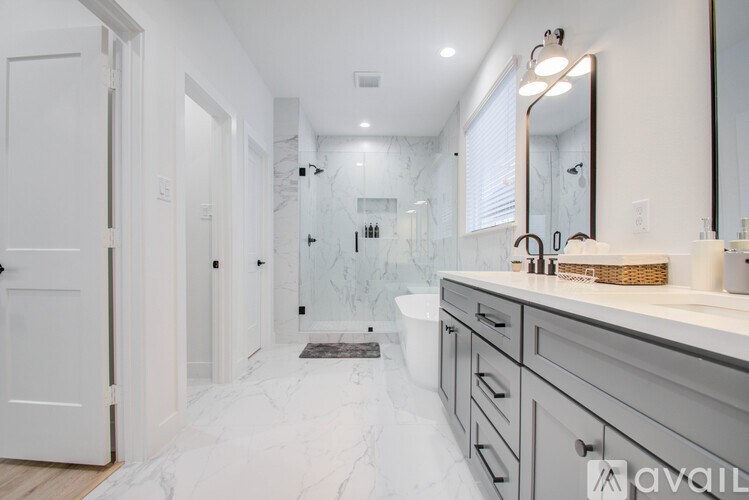 A bathroom with a marble floor and a large mirror above the sink.
