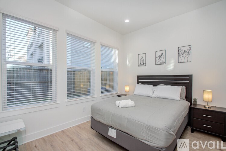 A bedroom with a large bed, two lamps, and pictures on the wall.