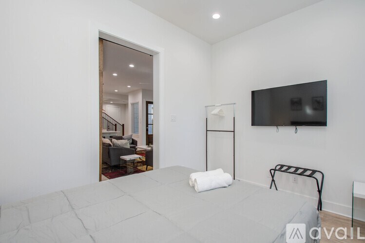 A bedroom with a bed, a chair, and a television mounted on the wall.