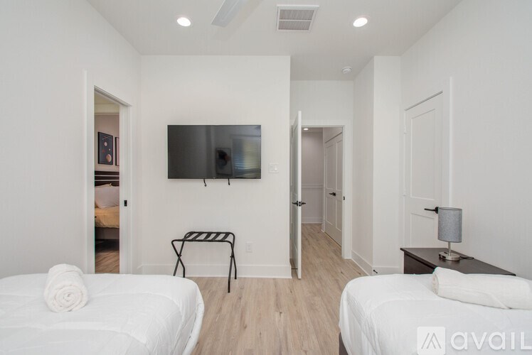 A bedroom with two beds and a television mounted on the wall.
