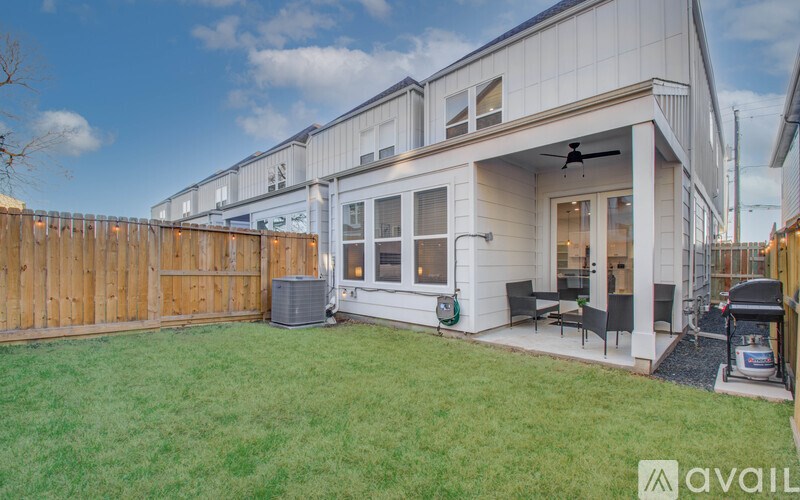 A house with a white exterior and a patio with a table and chairs.