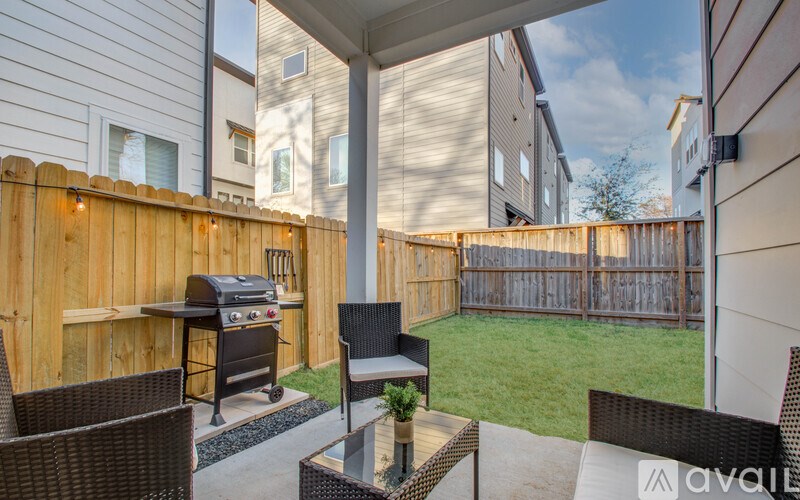A patio with a table, chairs, and a grill.