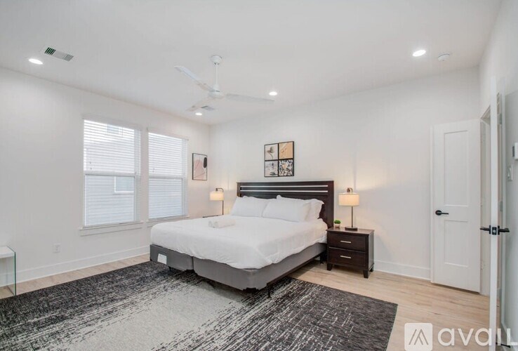 A bedroom with a large bed, a ceiling fan, and a rug on the floor.