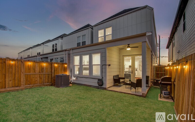 A modern house with a wooden fence and lights around the perimeter.