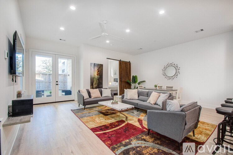 A living room with a grey couch and a rug.