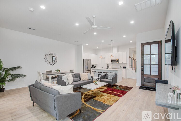 A living room with a grey couch and a rug with a wooden floor.