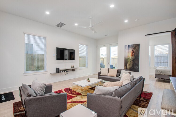 A living room with a grey couch and a rug.