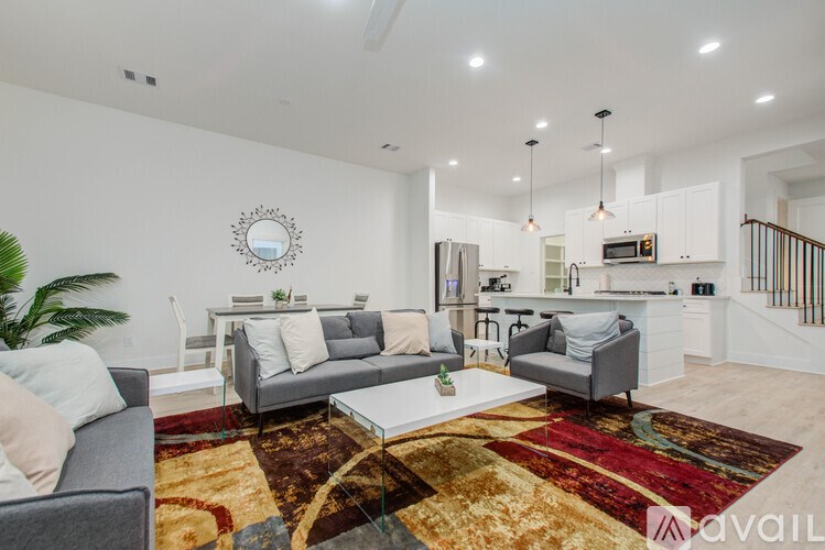 A living room with a grey couch, a white sofa, and a rug with a mix of red, yellow, and brown patterns.