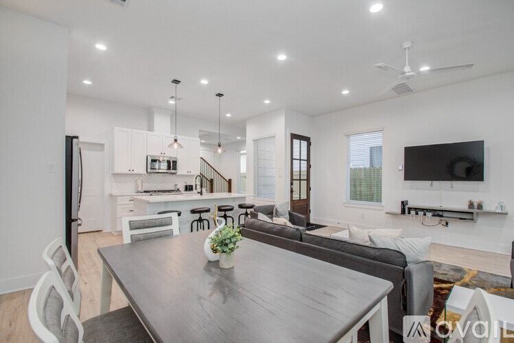 A modern dining room with a dark wood table and white chairs.