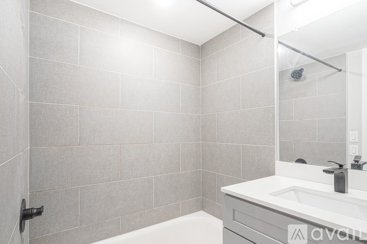 A bathroom with a white sink and grey tiles.