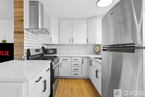 A kitchen with white cabinets and a black door.