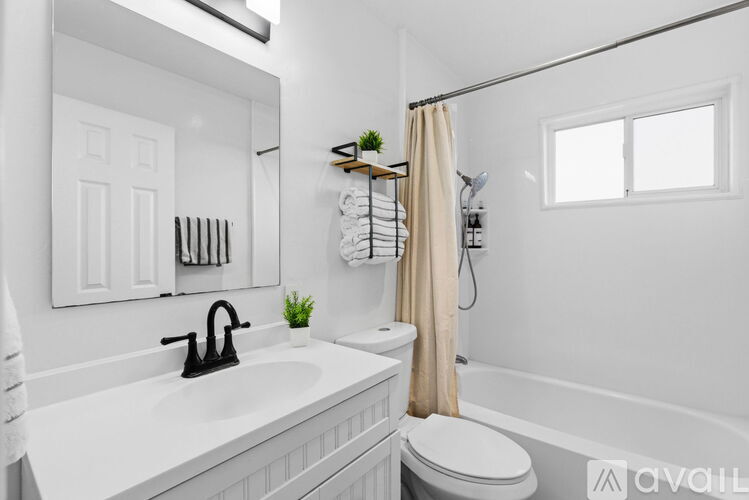 A white bathroom with a sink, mirror, and bathtub.