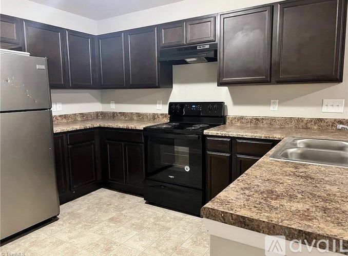 A kitchen with black cabinets and a granite countertop.