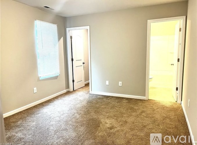 A room with carpeted floor and two doors.