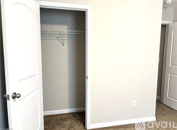 A white door is open to a small closet with a shelf.