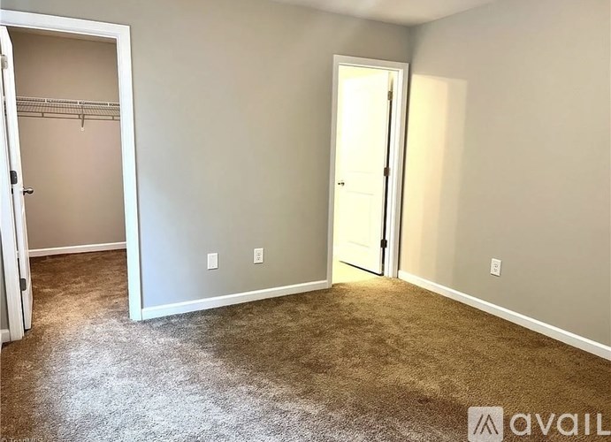 A room with a carpeted floor and two doors, one of which is open.