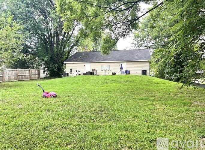 A lawn mower is on the grass in front of a house.