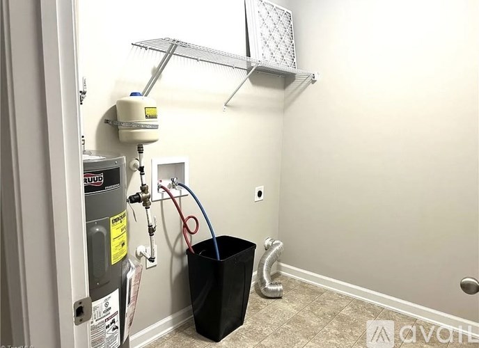 A room with a wall-mounted air conditioning unit and a black trash can.