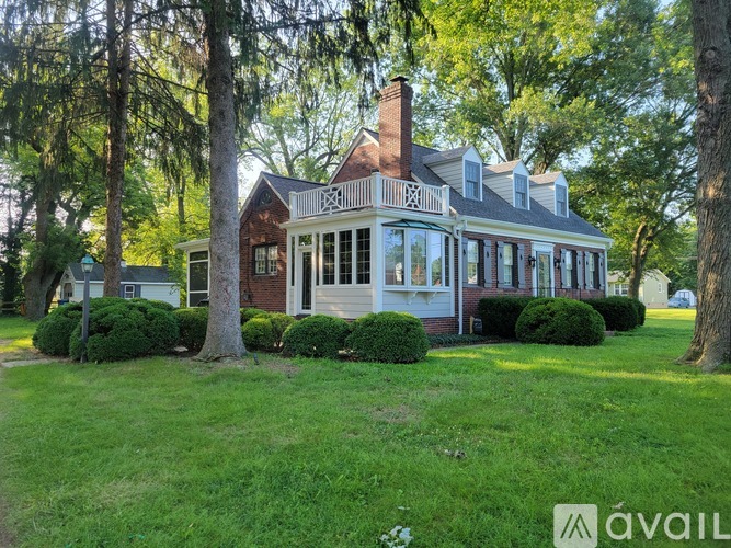 A house with a red brick chimney is surrounded by greenery.