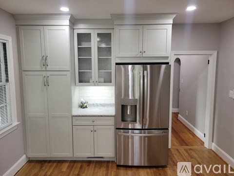 A kitchen with a stainless steel refrigerator and white cabinets.