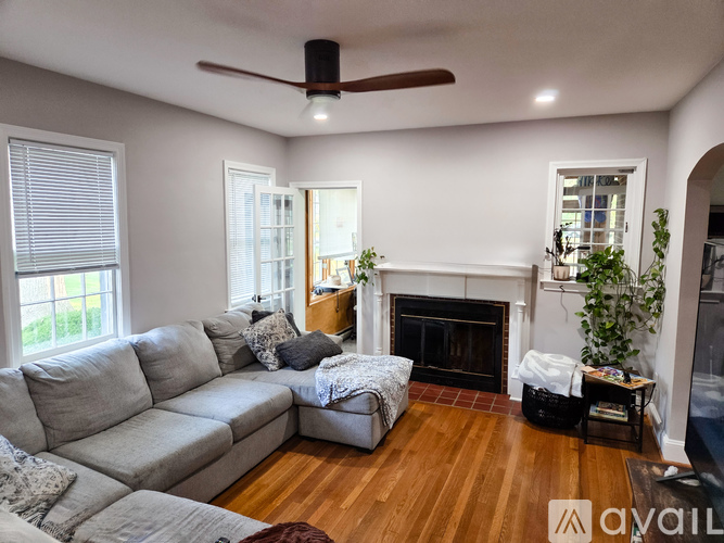 A living room with a grey sectional sofa, a fireplace, and a ceiling fan.