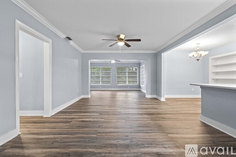 A spacious living room with a kitchenette and hardwood flooring.