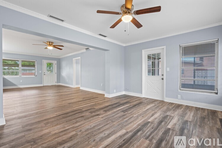 A spacious room with a ceiling fan and wooden flooring.
