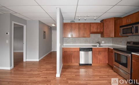 A kitchen with wooden cabinets and a white trash can.