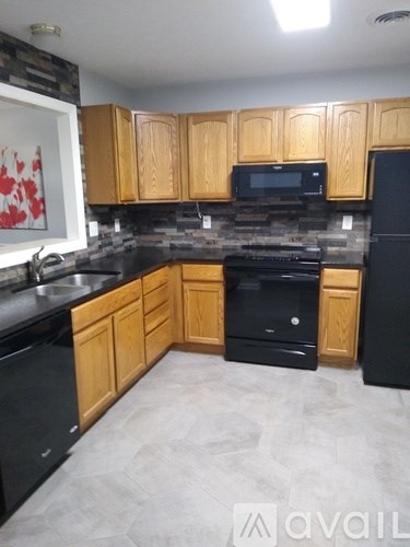 A kitchen with wooden cabinets and black appliances.