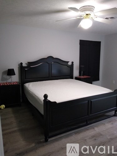 A bedroom with a bed, nightstand, and lamp.