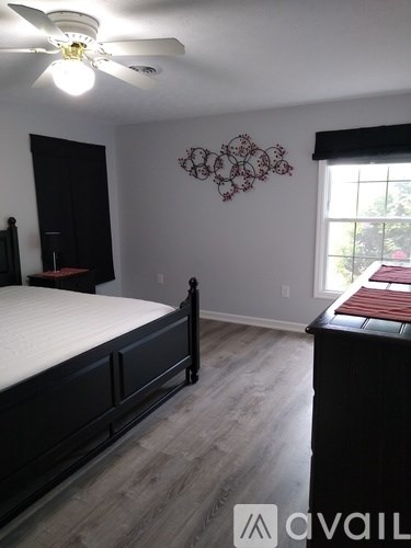A bedroom with a bed, dresser, and ceiling fan.