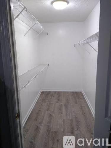 A walk-in closet with shelves and a wooden floor.
