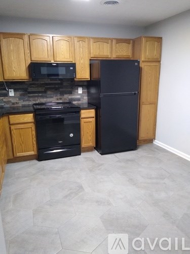 A kitchen with wooden cabinets and black appliances.