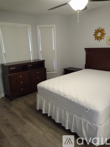 A bedroom with a bed, nightstand, and dresser.