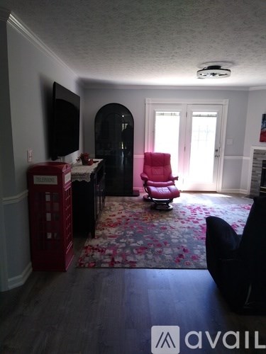 A living room with a red chair and a black couch.