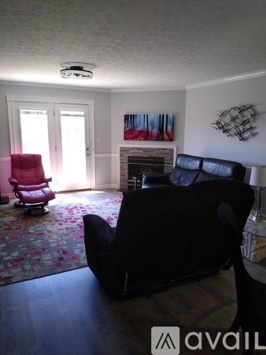A living room with a black couch and a red chair.