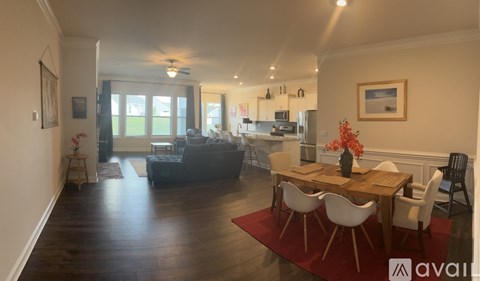 A living room with a dining table and chairs in the foreground and a kitchen in the background.