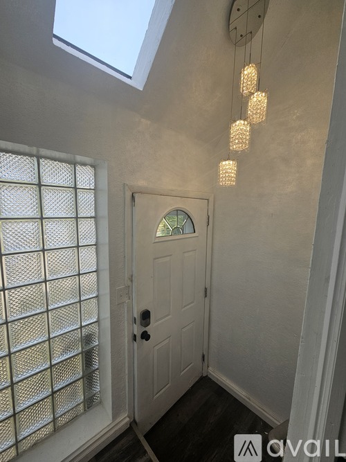 A white door is in a hallway with a skylight above it.