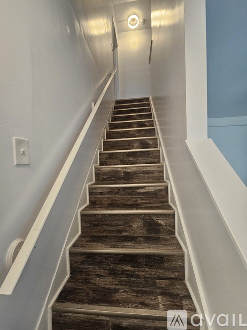 A long flight of stairs with a light on the wall.