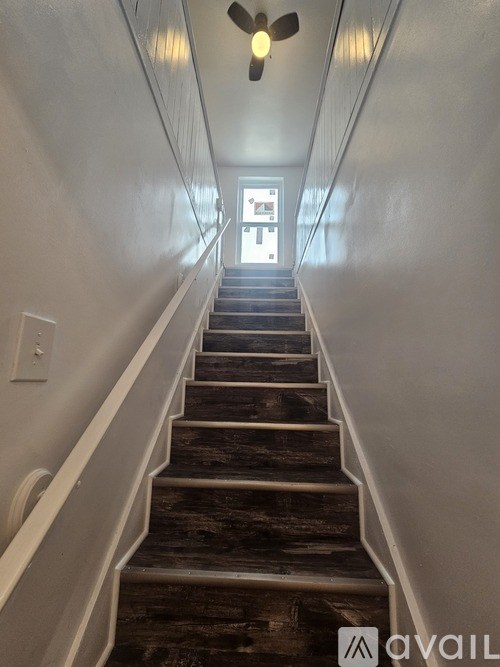 A staircase with wooden steps and white railings leading to a door.