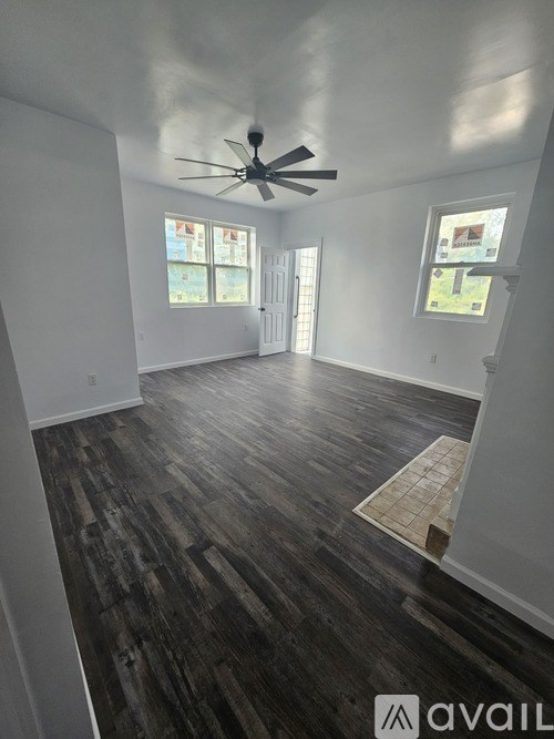 A room with a ceiling fan and wood flooring.