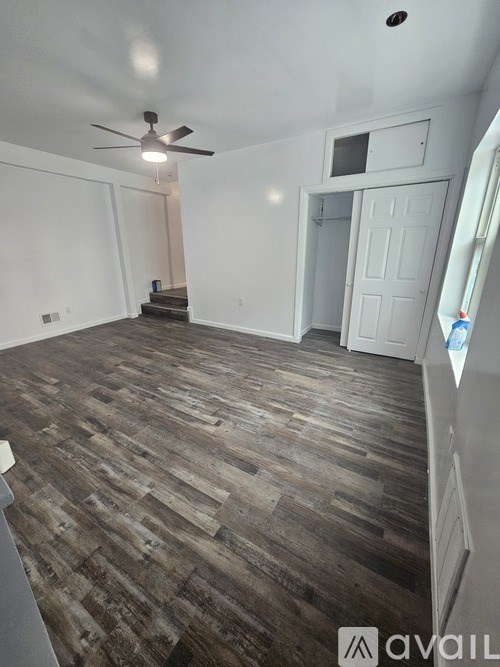 A room with a ceiling fan and wooden flooring.