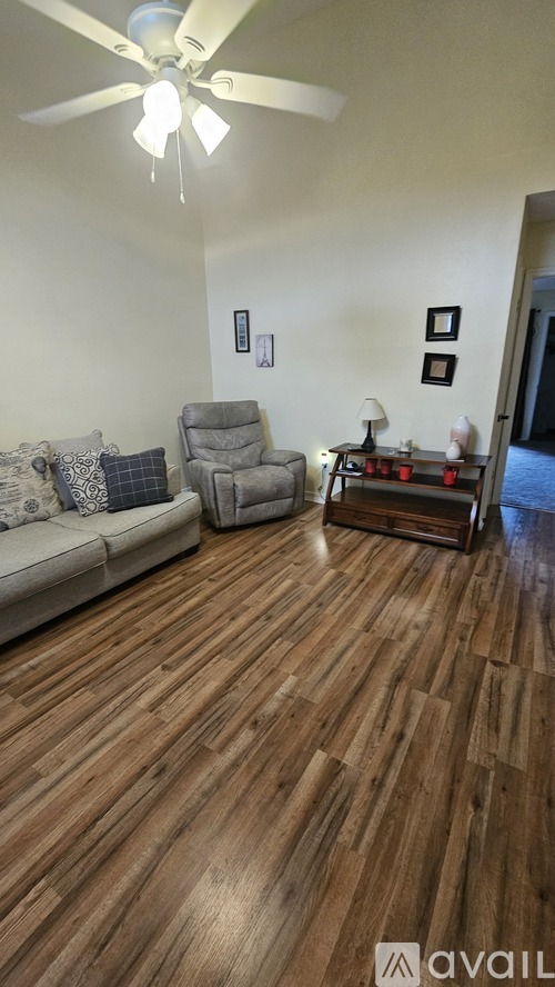 A living room with a couch, chair, and a ceiling fan.