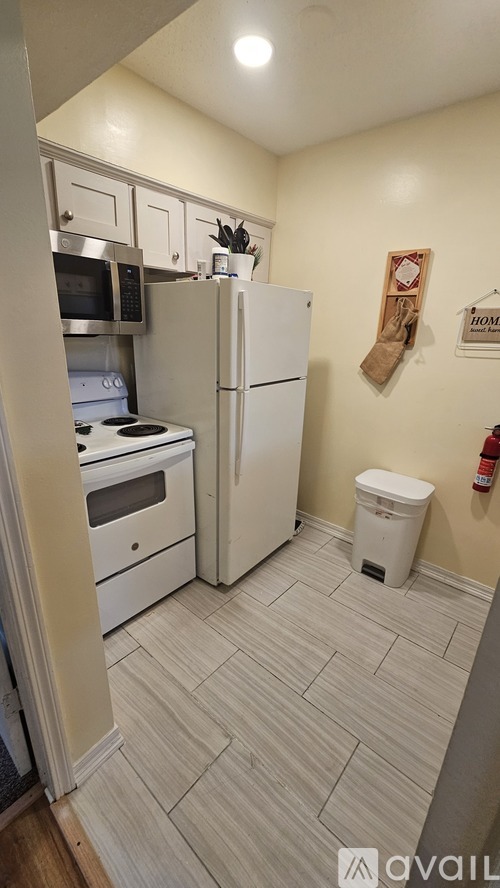 A kitchen with a white fridge and a white toilet.