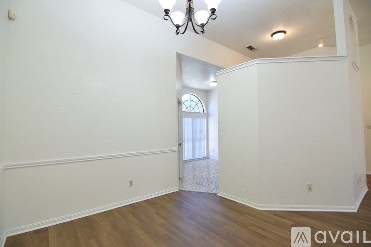 A room with a chandelier and a window with blinds.