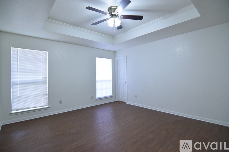 A room with a ceiling fan and wooden flooring.