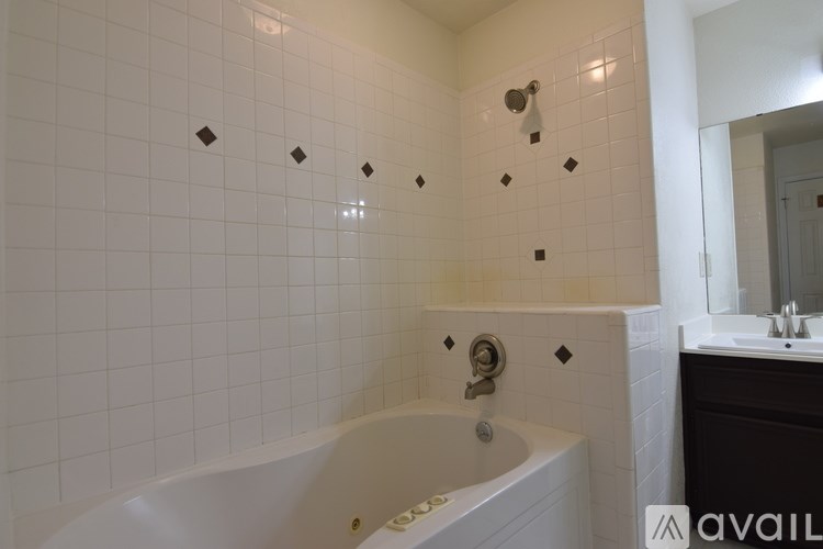 A white bathtub in a bathroom with a black vanity and mirror.